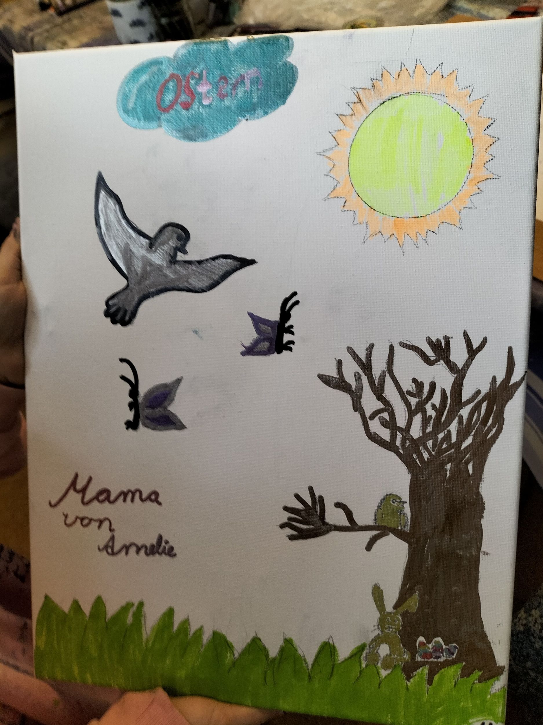 Eine gemalte Frühlingsszene mit Sonne, Baum, Vögeln, Gras und dem Wort Ostern