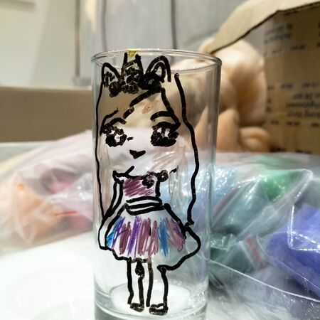 Ein Glas mit einer bunten Zeichnung eines Mädchens mit Katzenohren und Kleid