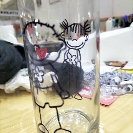 Ein durchsichtiges Glas mit schwarzen Zeichnungen von zwei lächelnden Kindern darauf