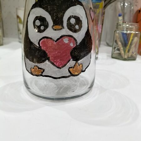 Ein fröhlicher schwarz weißer Pinguin mit rosa Herz ist auf ein Glas gemalt