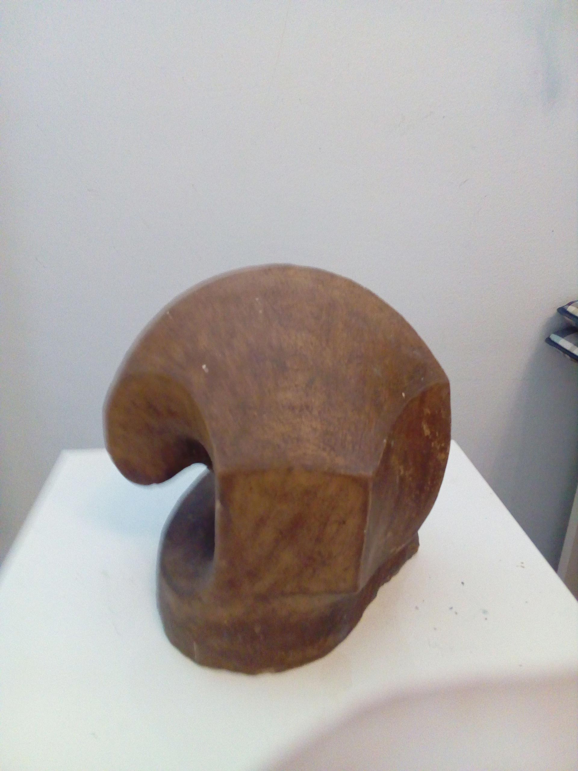 Eine abstrakte braune Skulptur mit geschwungener Form auf weißer Oberfläche