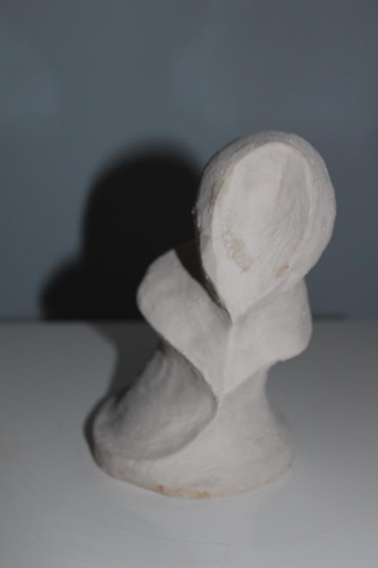 Eine abstrakte weiße Skulptur mit weichen Rundungen vor blauem Hintergrund