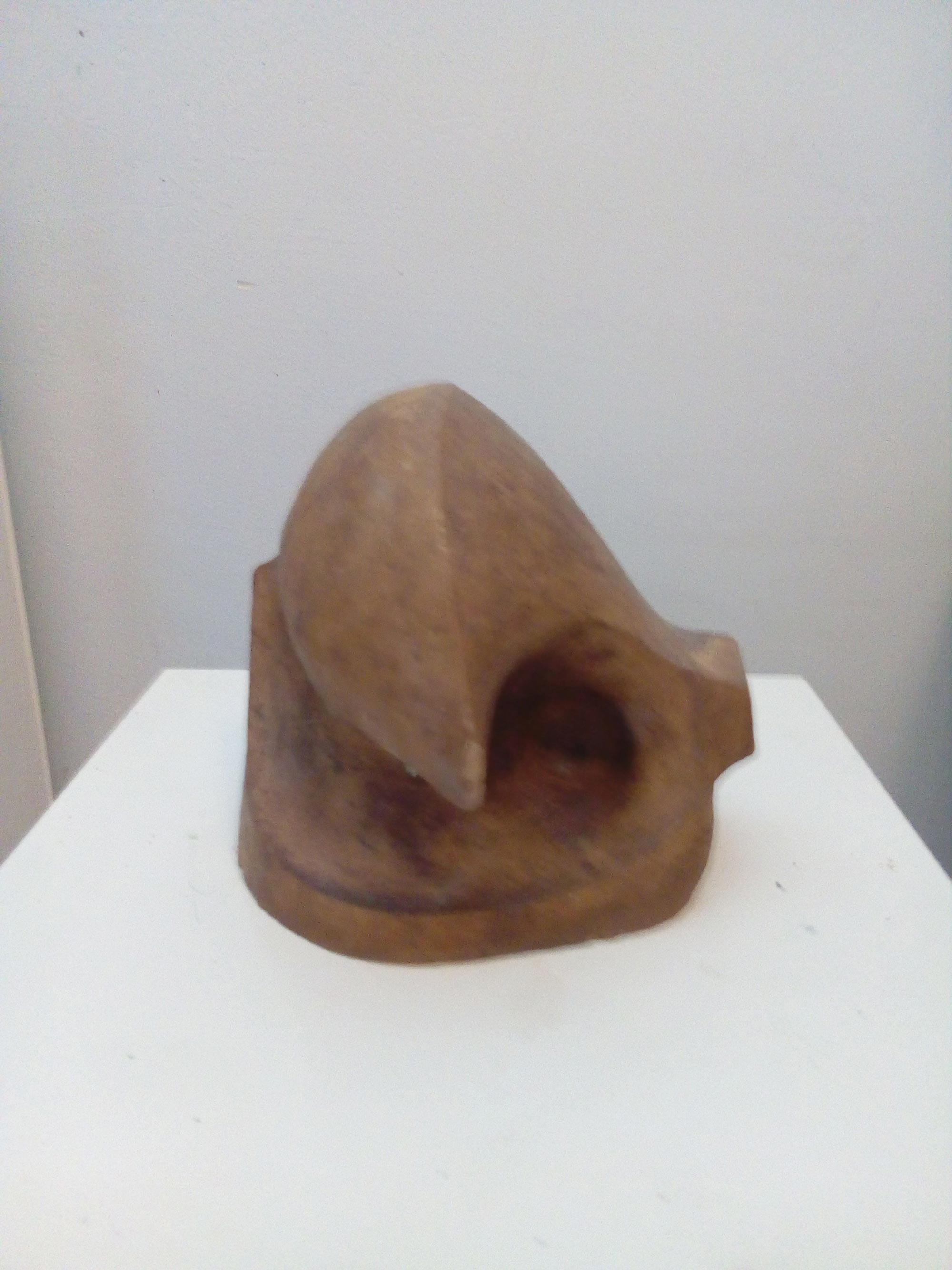 Eine abstrakte braune Skulptur mit geschwungenen Formen auf weißem Sockel