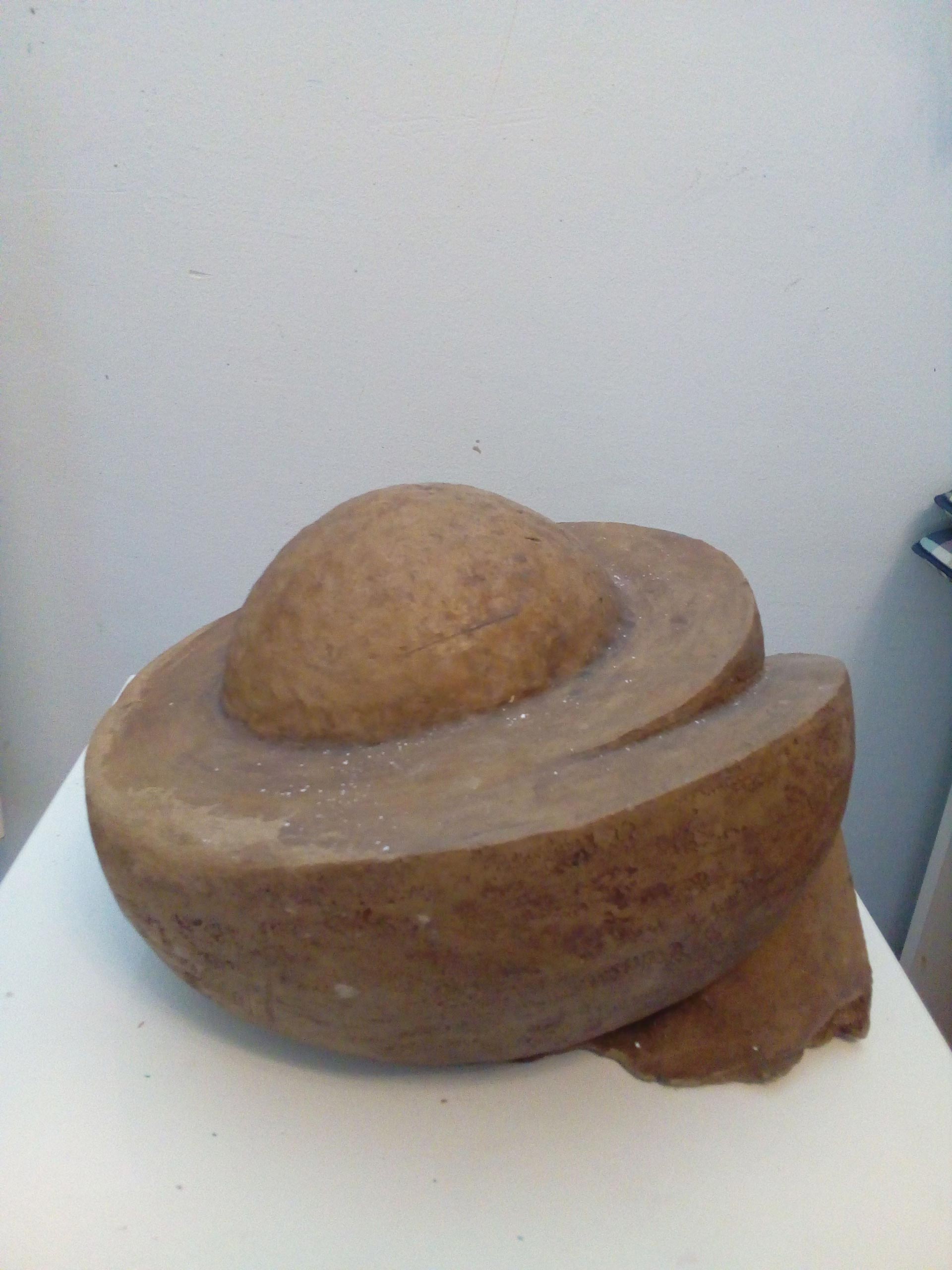 Eine braune Skulptur mit runden und gewundenen Formen auf hellem Untergrund