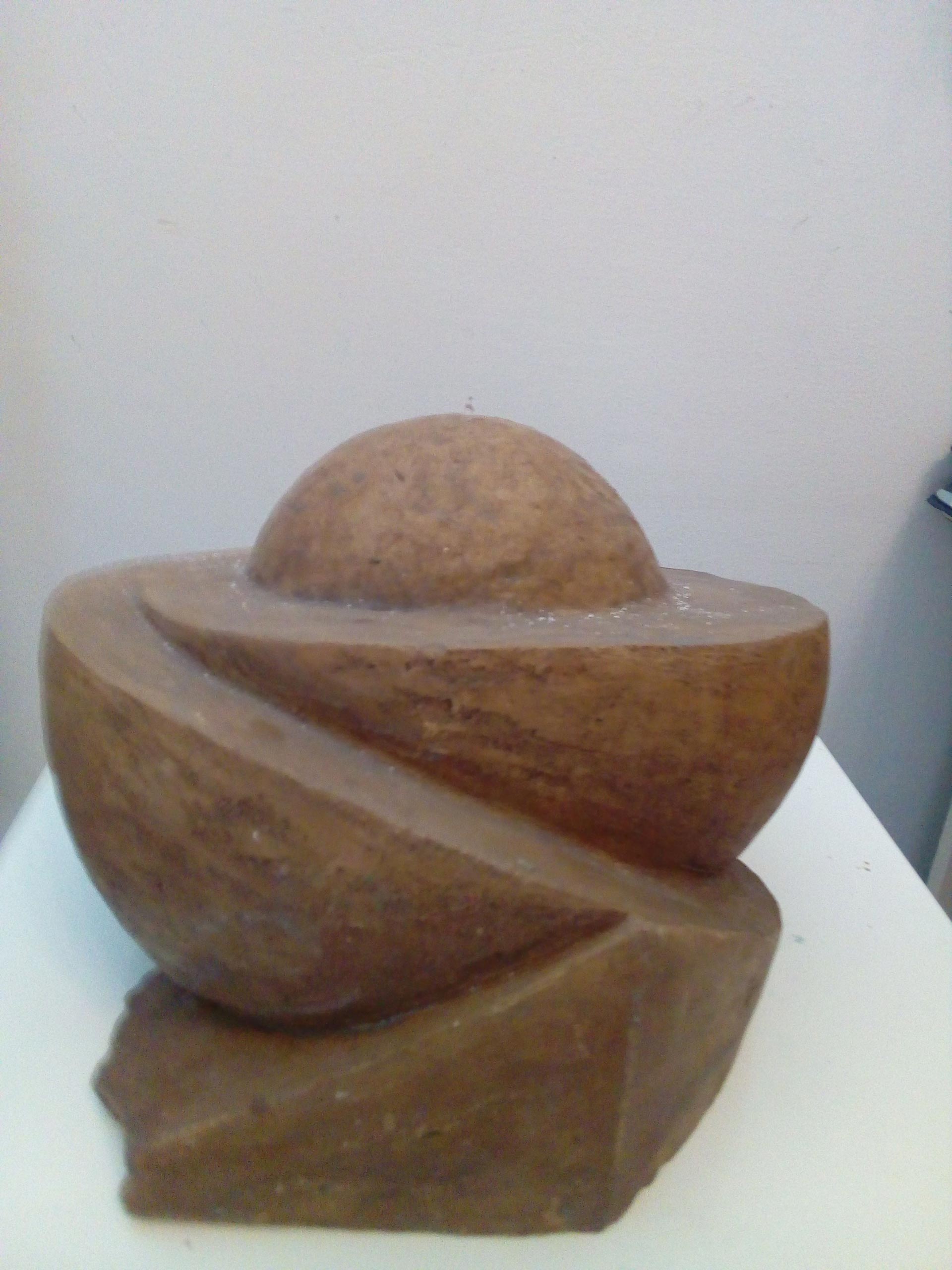 Eine braune Steinskulptur mit spiralförmigem Muster und halbkugelförmiger Kuppe