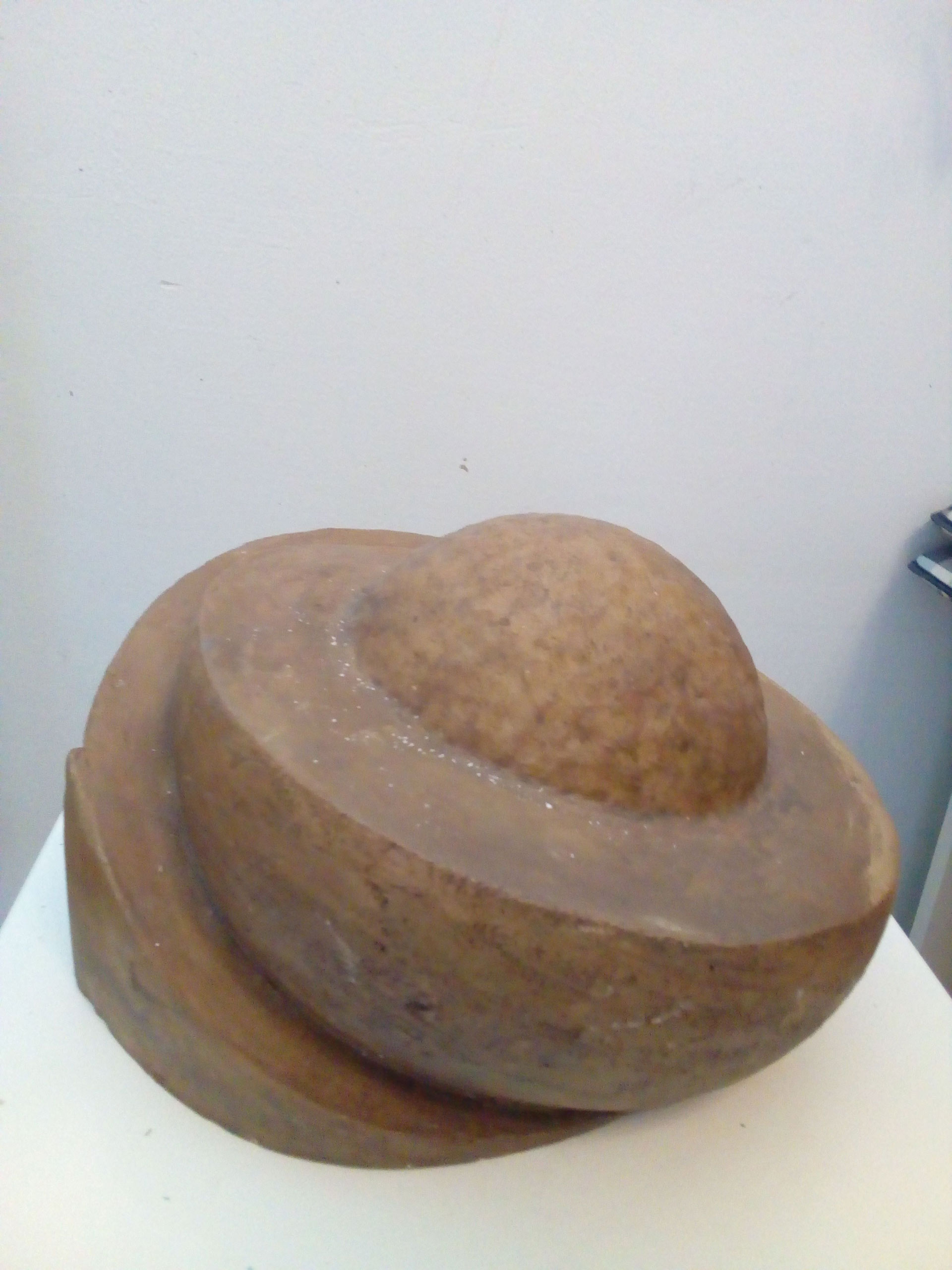 Eine Skulptur aus braunem Stein erinnert an einen Planeten mit auffälligem Ring