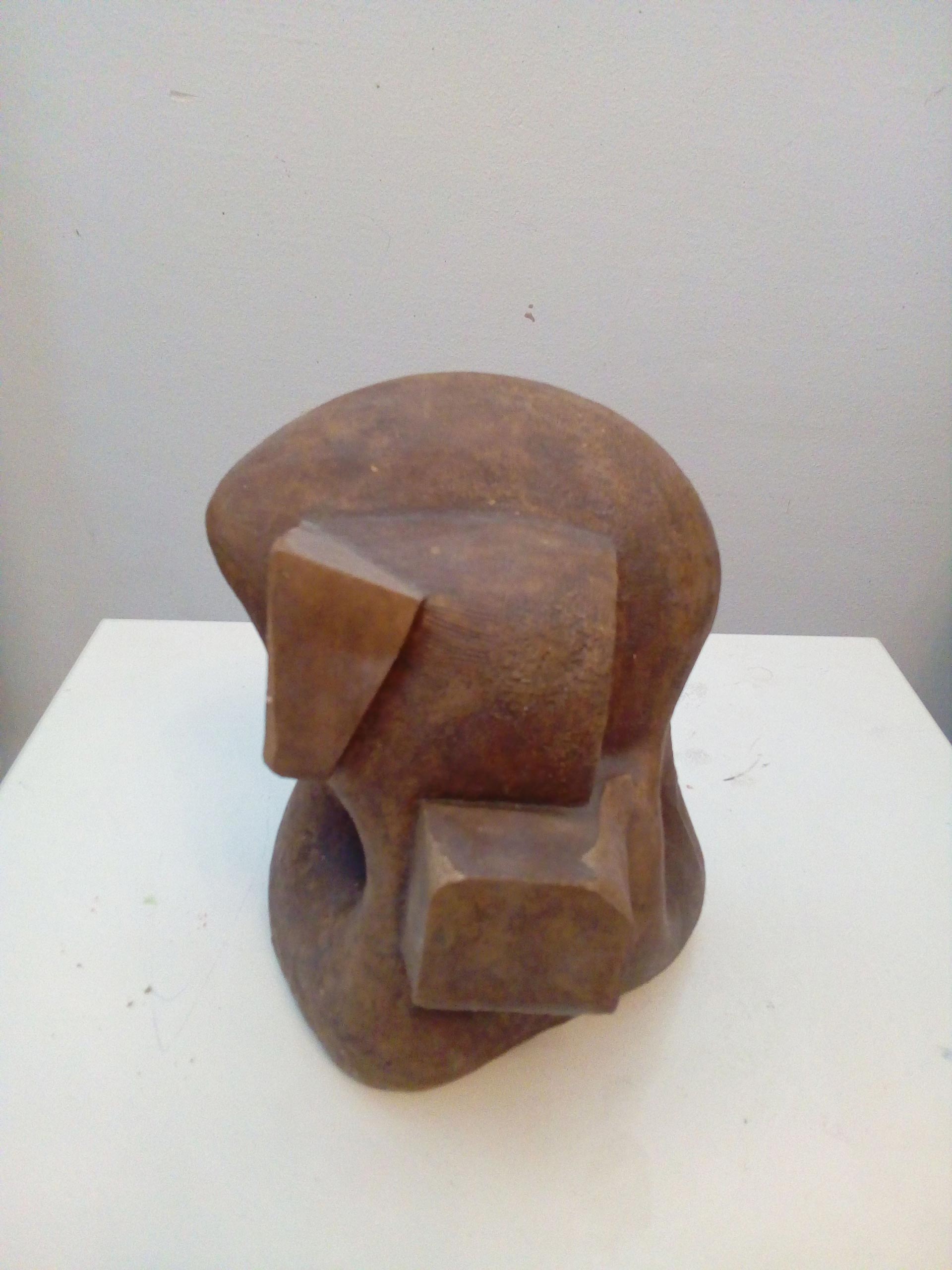 Abstrakte braune Skulptur mit geometrischen Formen und glatter Oberfläche auf weißem Sockel