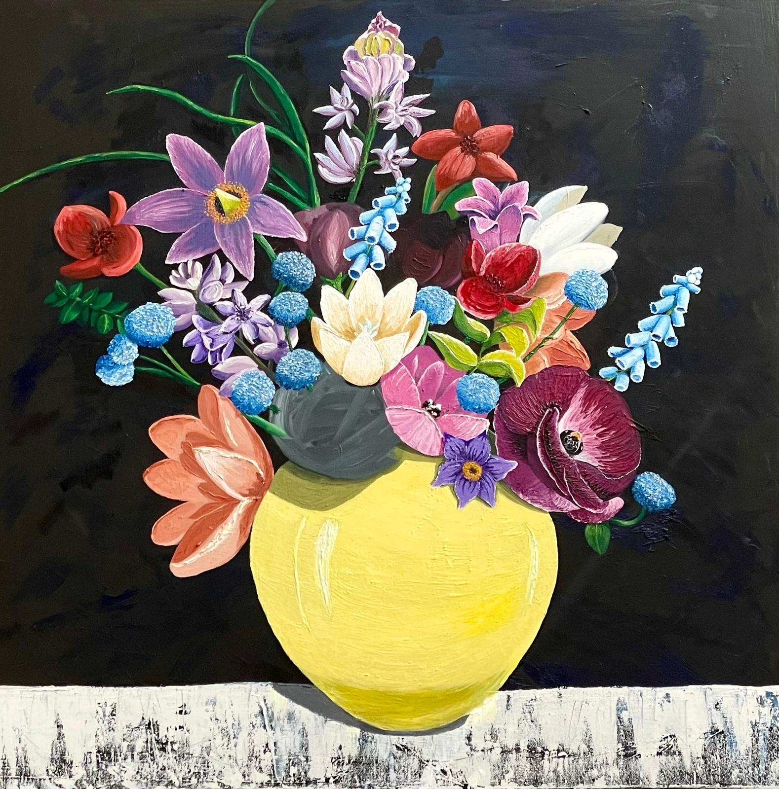 Ein gelber Keramikkrug mit bunten Blumen vor schwarzem Hintergrund auf einem Holztisch