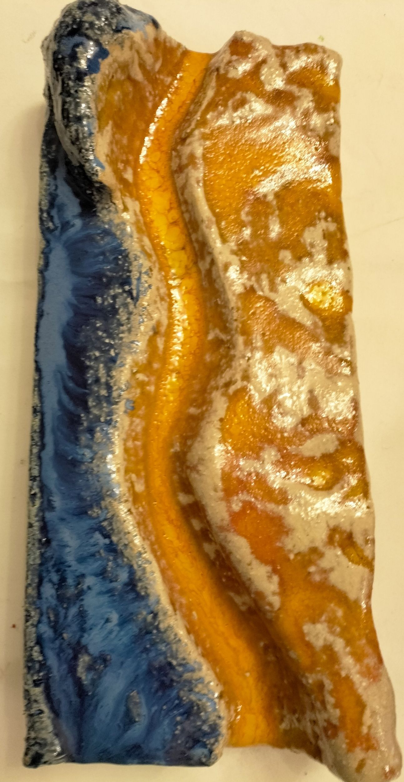 Keramikstück mit welligen blauen und orangefarbenen Formen sowie glänzenden Akzenten