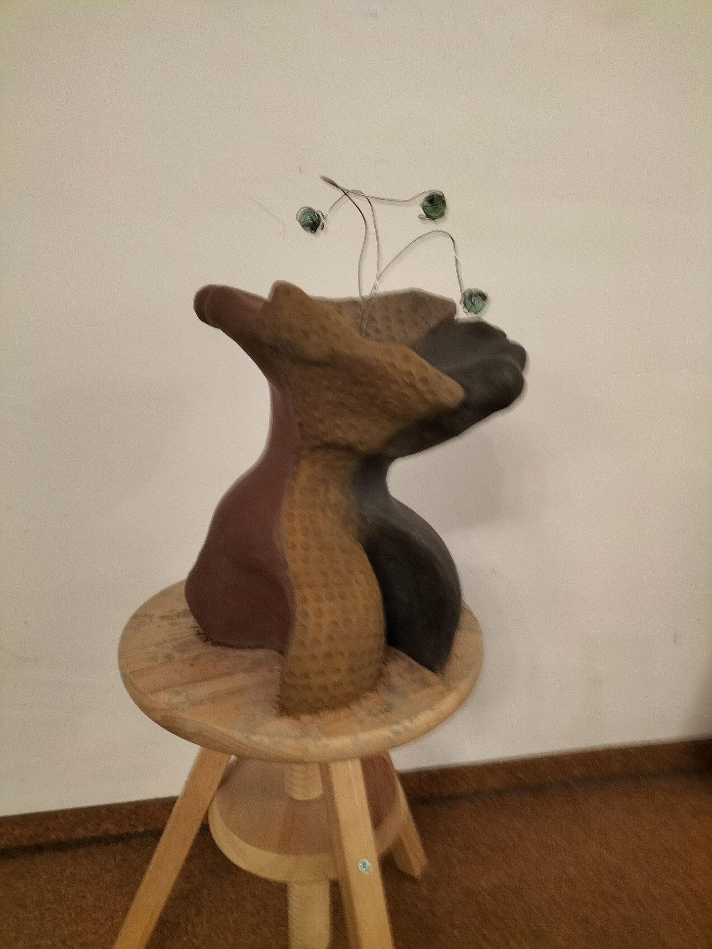 Abstrakte Skulptur mit rauen braunen und schwarzen Oberflächen auf einem Holzstuhl