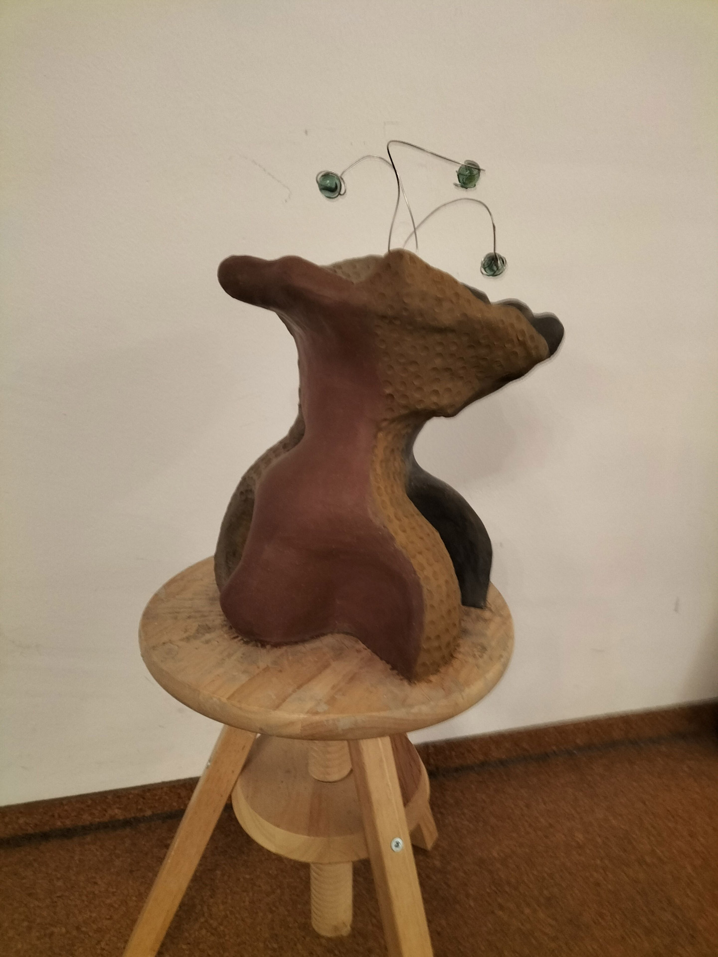 Abstrakte Skulptur mit braunen und schwarzen Farben auf einem Hocker mit Drahtspiralen