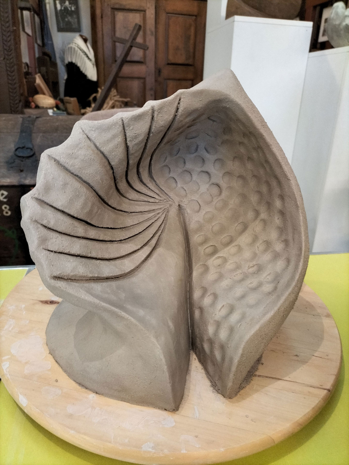 Tonfarbene abstrakte Skulptur mit spiralförmigen Linien und punktiertem Muster