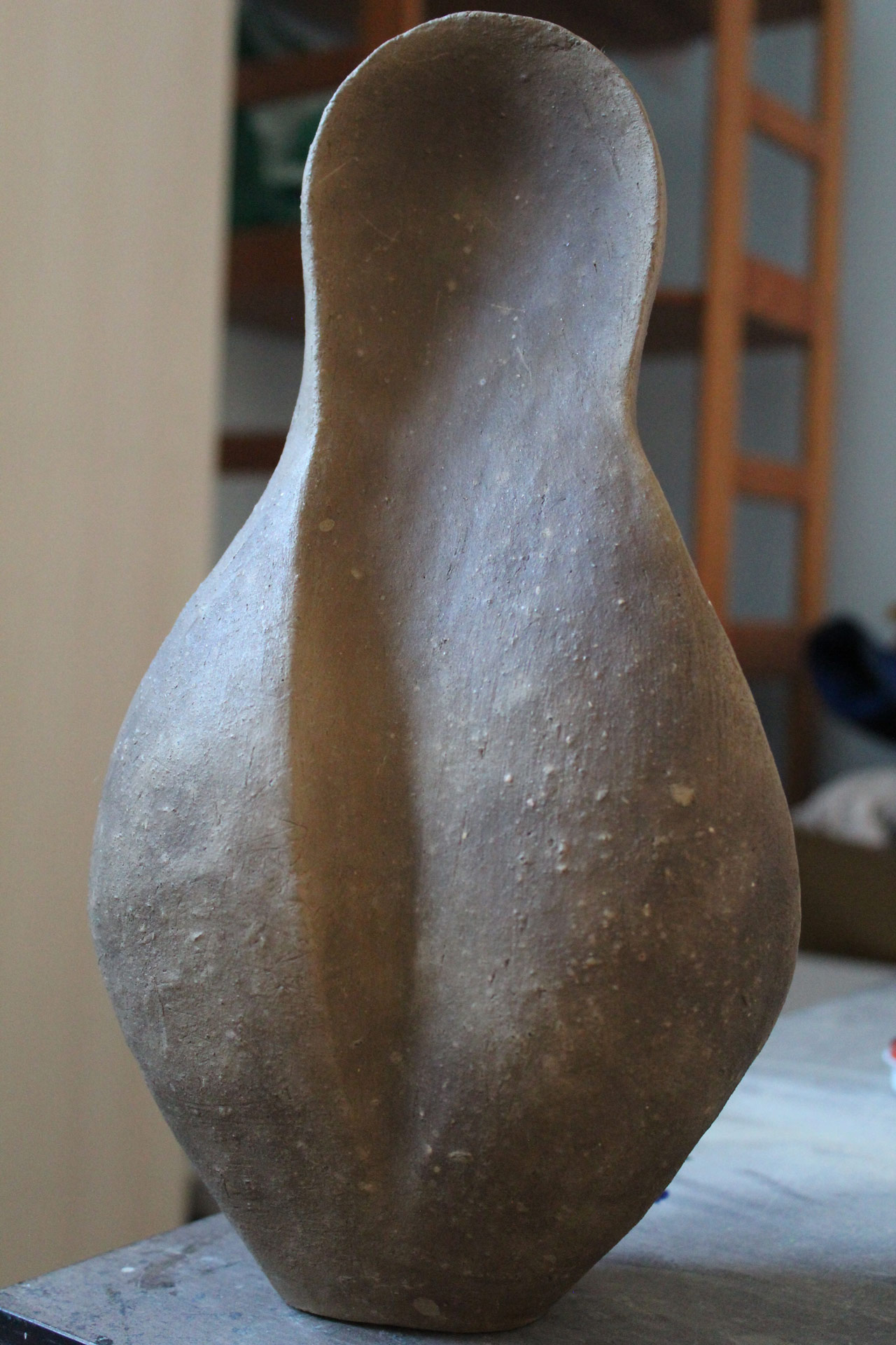Eine braune, strukturiert wirkende Skulptur mit organischer, bauchiger Form