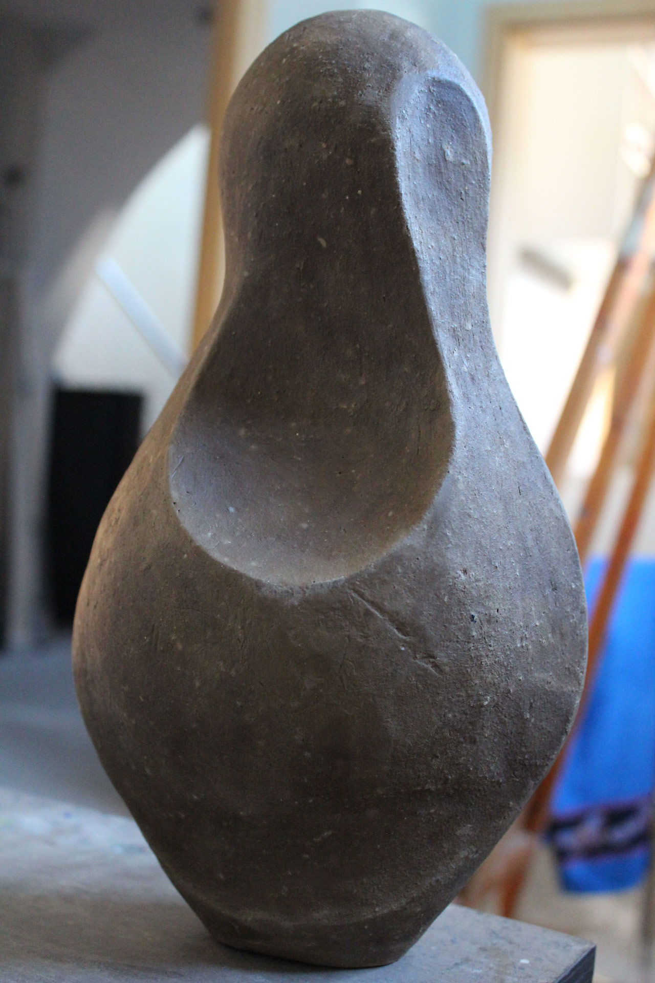 Eine abstrakte braune Skulptur mit runden Formen und glatter Oberfläche steht im Licht