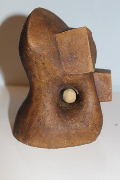 Eine abstrakte braune Skulptur mit organischen und eckigen Formen und Kugel im Loch