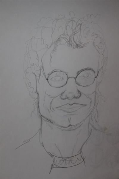 Eine lockige Person mit freundlichem Gesichtsausdruck trägt eine runde Brille