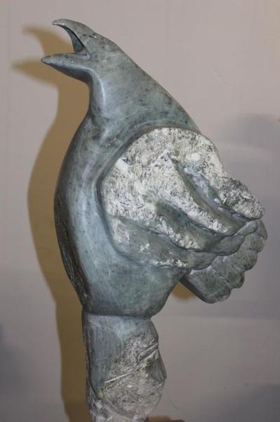 Eine graue Skulptur eines Vogels mit geöffnetem Schnabel und erhobenem Flügel