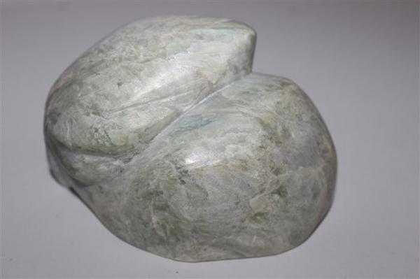 Grauer, glänzender Stein in Form eines sitzenden Kaninchens mit glatten Flächen
