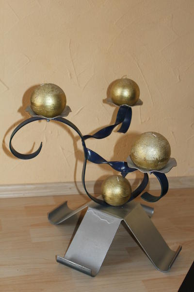 Modern silberner Kerzenhalter aus Metall mit goldenen Kugeln auf hellem Holzboden