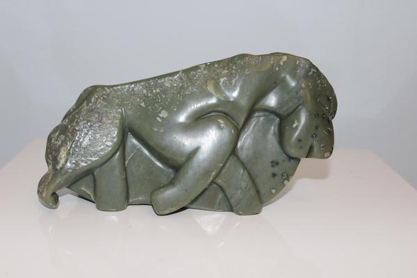 Eine grüne Steinskulptur zeigt einen liegenden Löwen mit ruhigem Ausdruck und glatter Oberfläche