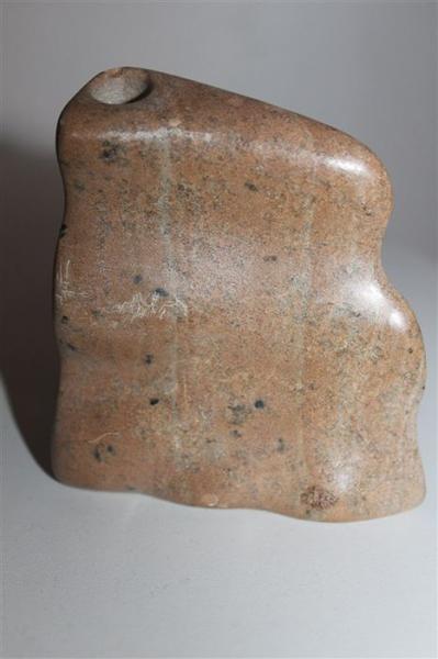 Ein abstrakter brauner Stein mit glatter Oberfläche und kleinen dunklen Flecken