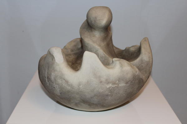 Eine abstrakte, grau-beige Skulptur mit runden Formen und einer zentralen Figur