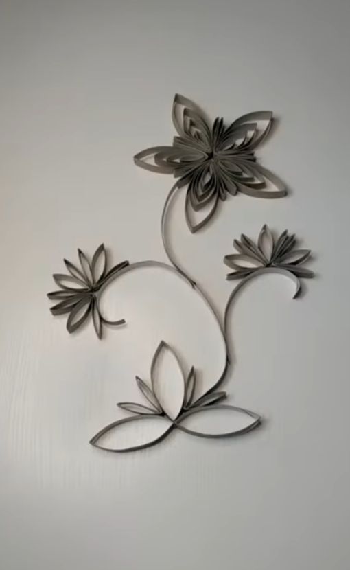 Graue Papierblueten an Wand als filigrane Ranken ohne Ausdruck
