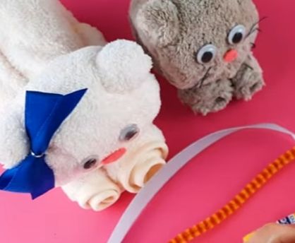 Zwei Stofftiere mit großen Augen, rosa Nasen auf pinkem Grund