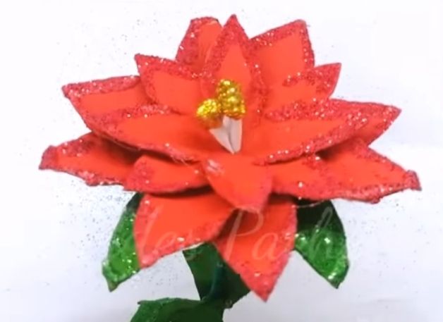 Rote Blume mit Glitzer, goldener Mitte und gruenen Blaettern, frisch