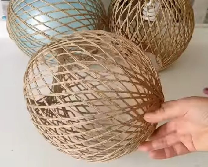 Hand hält beige geflochtene Kugel neben blauer und brauner Kugel