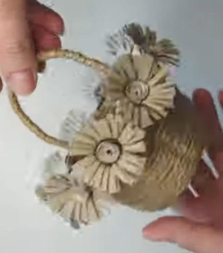 Haende halten beige Basttasche mit Blumen und geflochtenem Griff