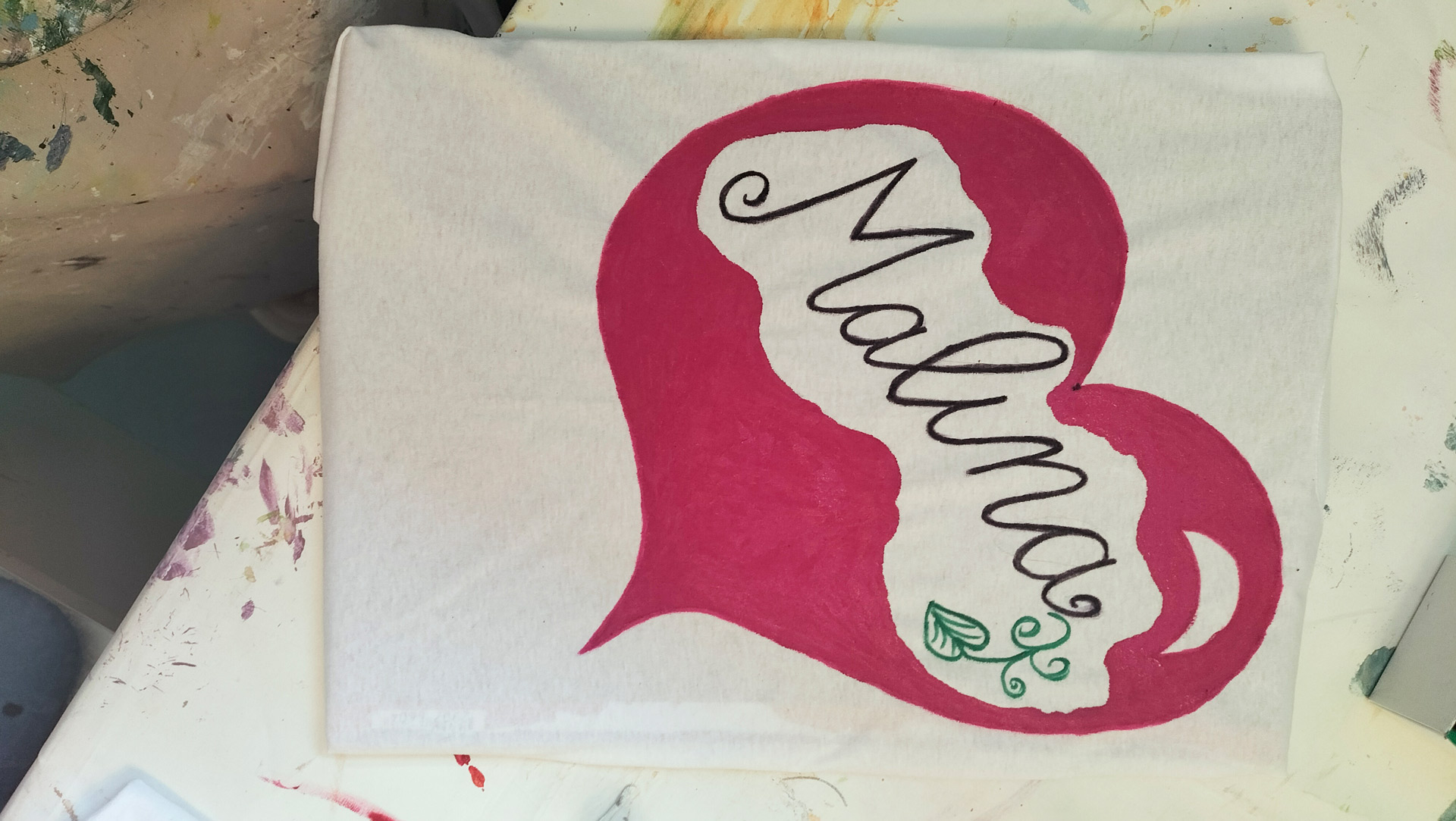 Gemalte pinke Haarsilhouette mit Schrift Malma und gruenem Blattornament