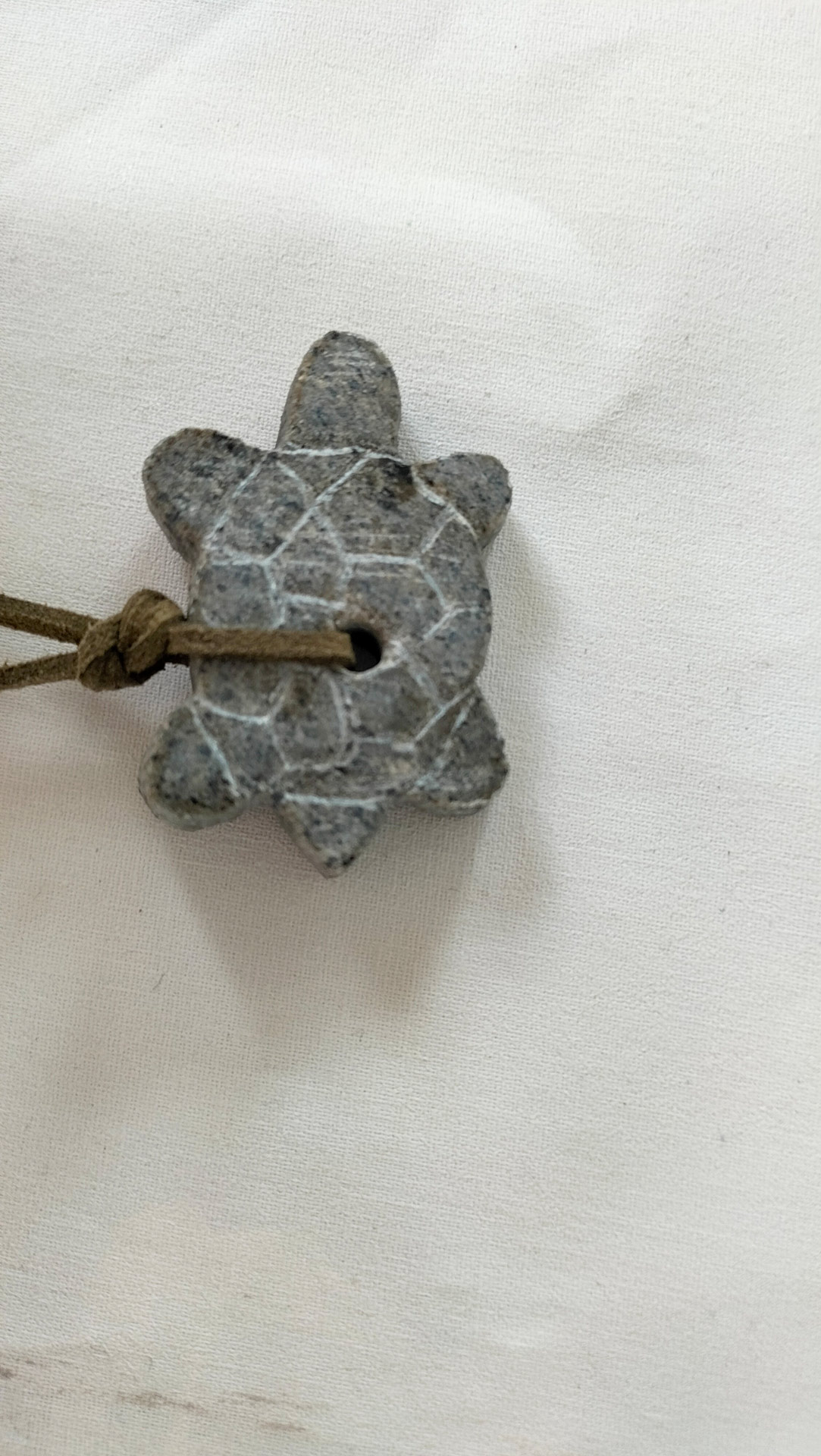 Grauer Schildkroetenanhaenger aus Stein mit Muster und braunem Band