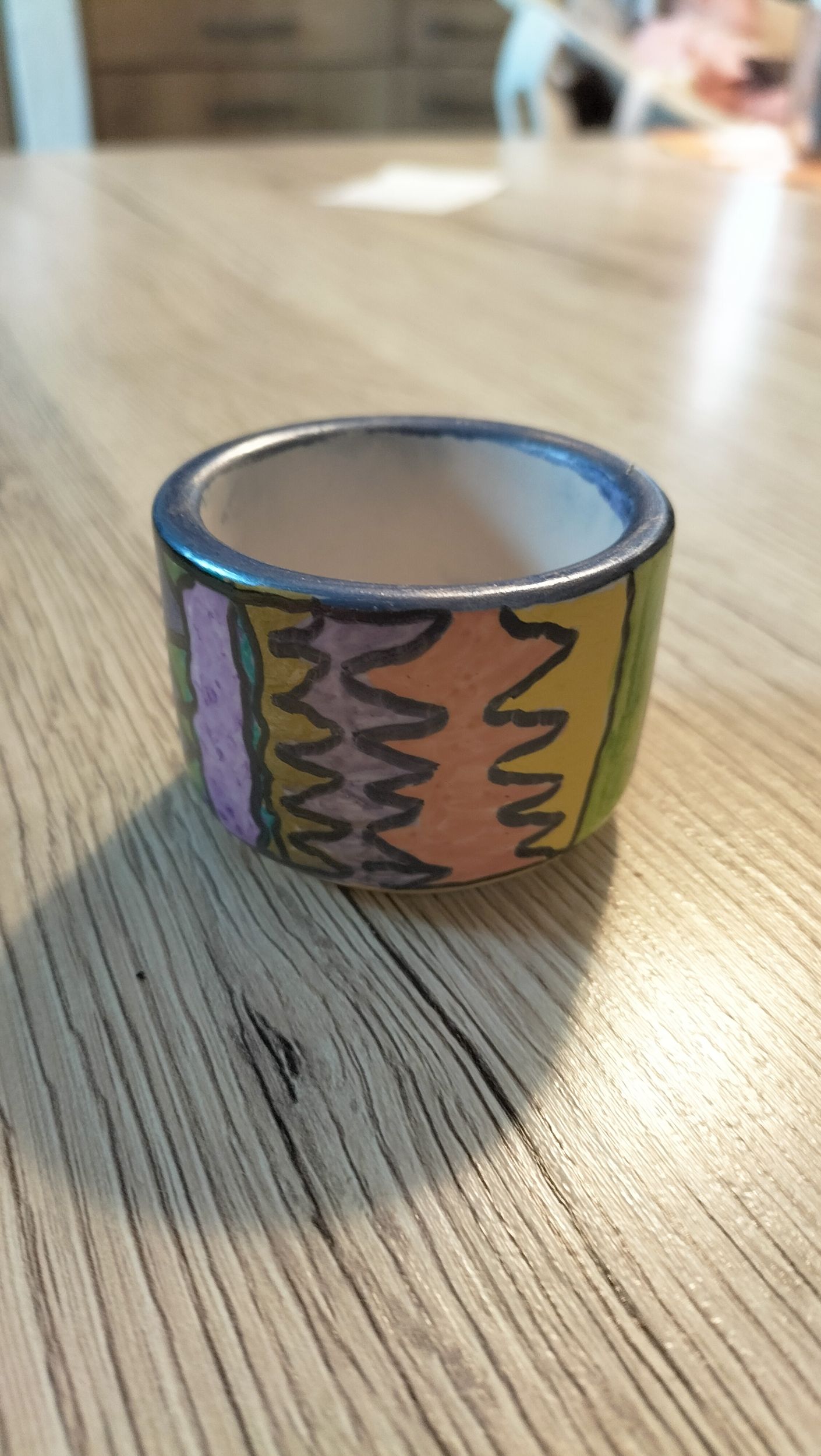 Bunter Klebebandring mit Zickzackmuster in Blau Gruen Lila auf Holz