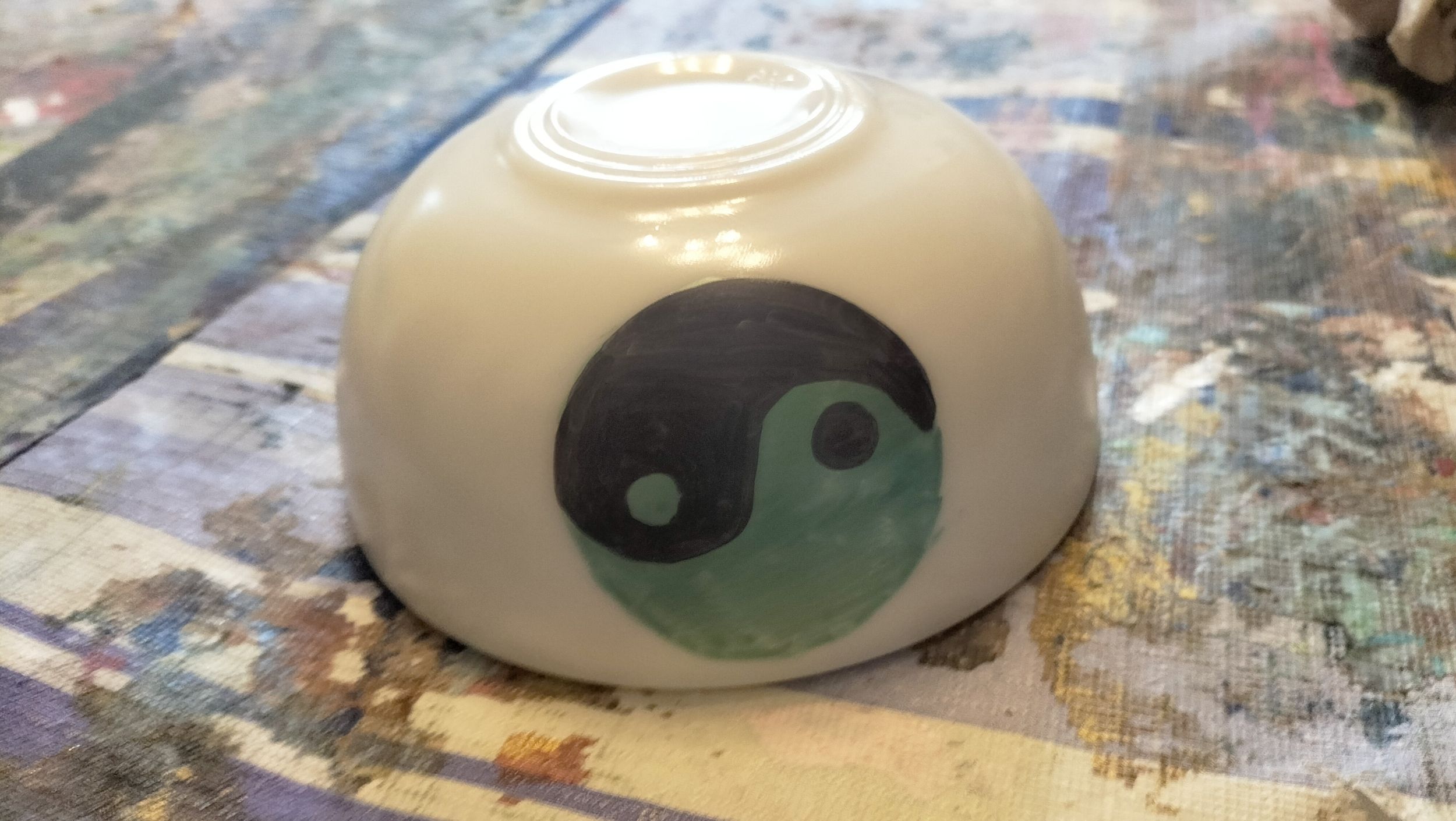 Umgedrehte weisse Schale mit Yin Yang Motiv in Schwarz und Gruen