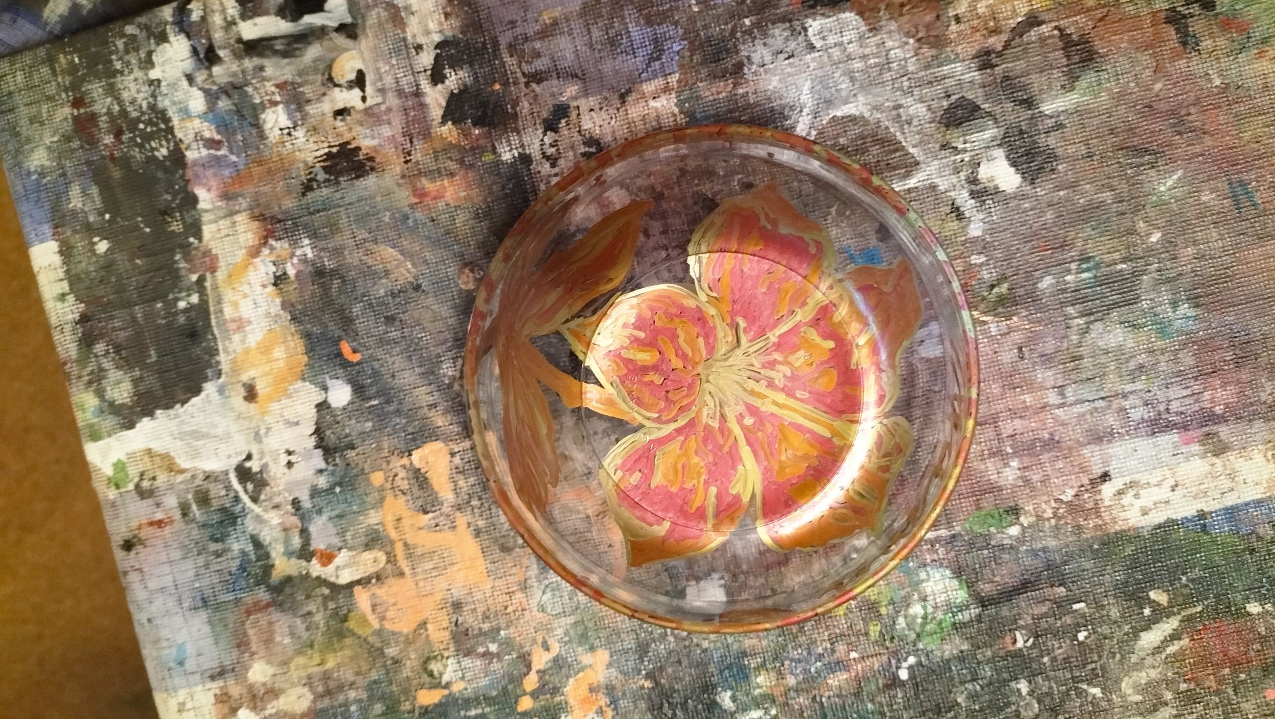 Bunte Grapefruitscheibe im Glas auf farbverschmiertem Maltisch, ruhig